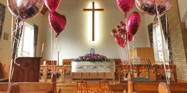 wool woolen coffin casket with pink balloons in church